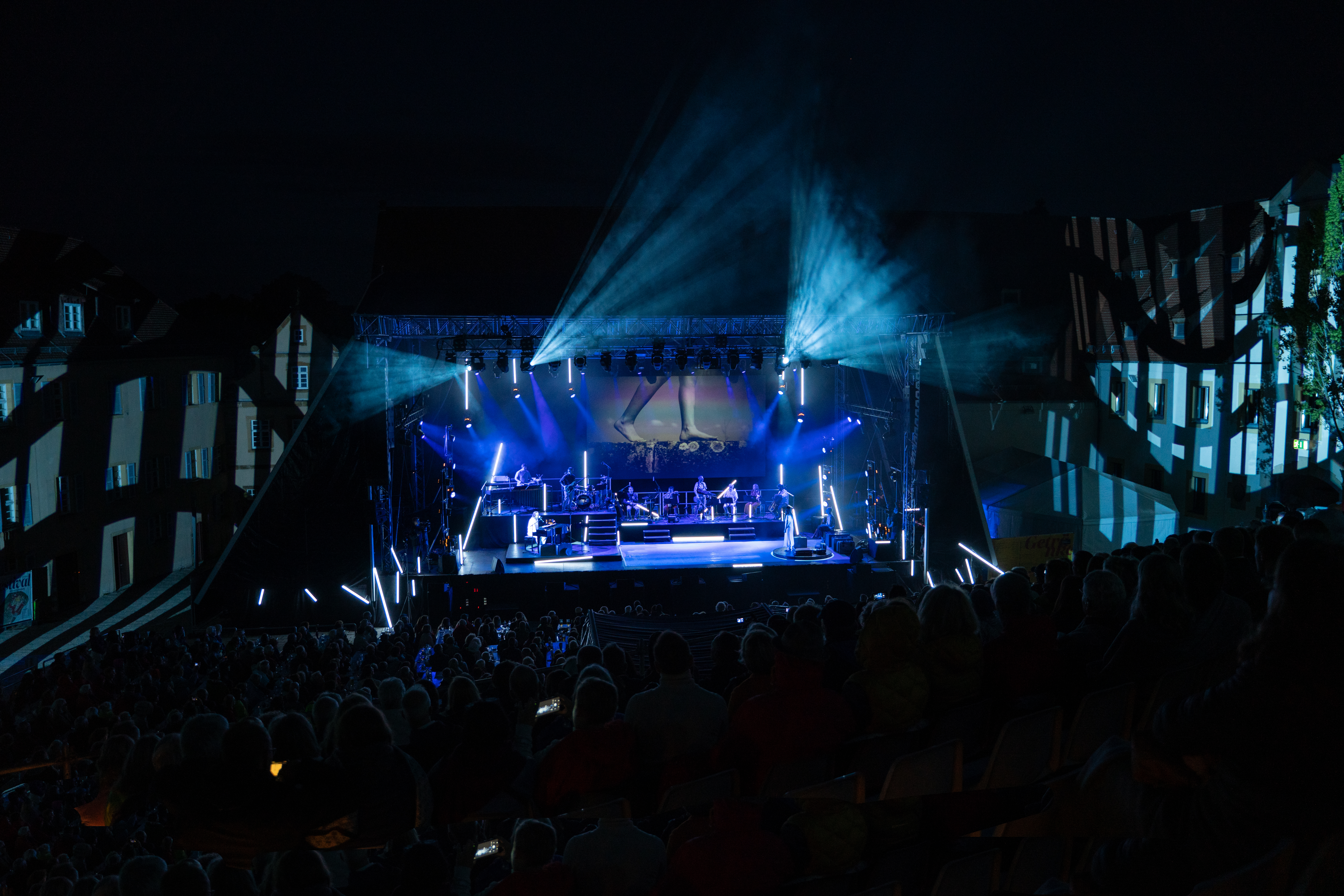 Publikum und Bühne verschmelzen in einer farbenfrohen Lichtshow bei einem Open-Air-Konzert